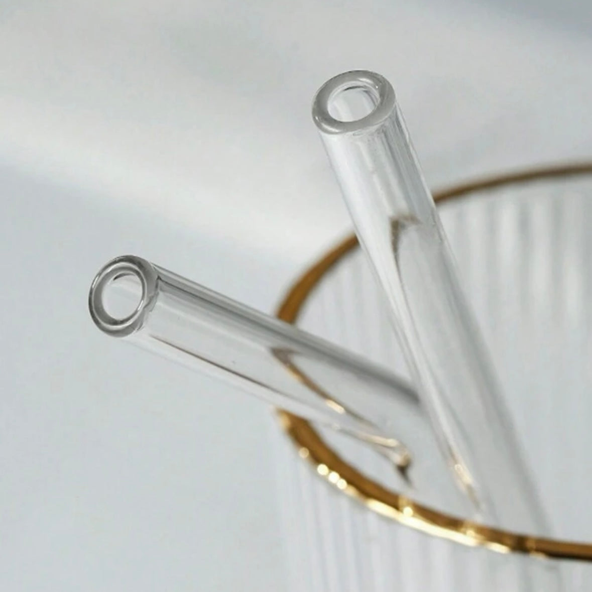 Glass straws being used with various beverages for stylish sipping.