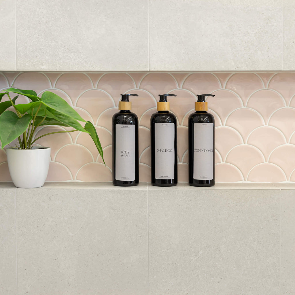 Pretty bathroom bottles with Luxe Minimalist Labels in white text, including 'Shampoo', 'Conditioner', and 'Body Wash