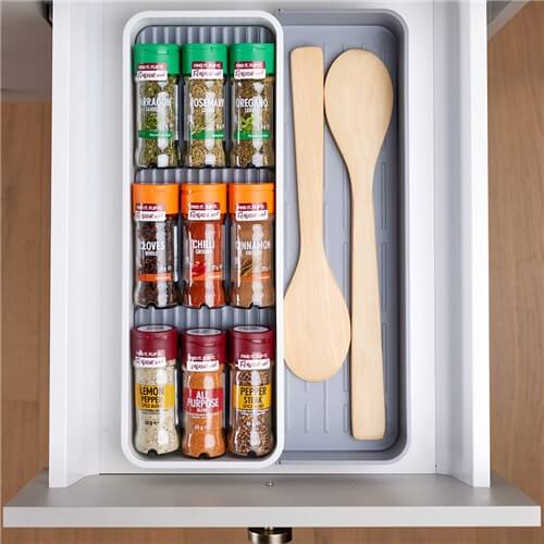 Tiered spice drawer organiser displayed in a kitchen, preventing jars from rolling.