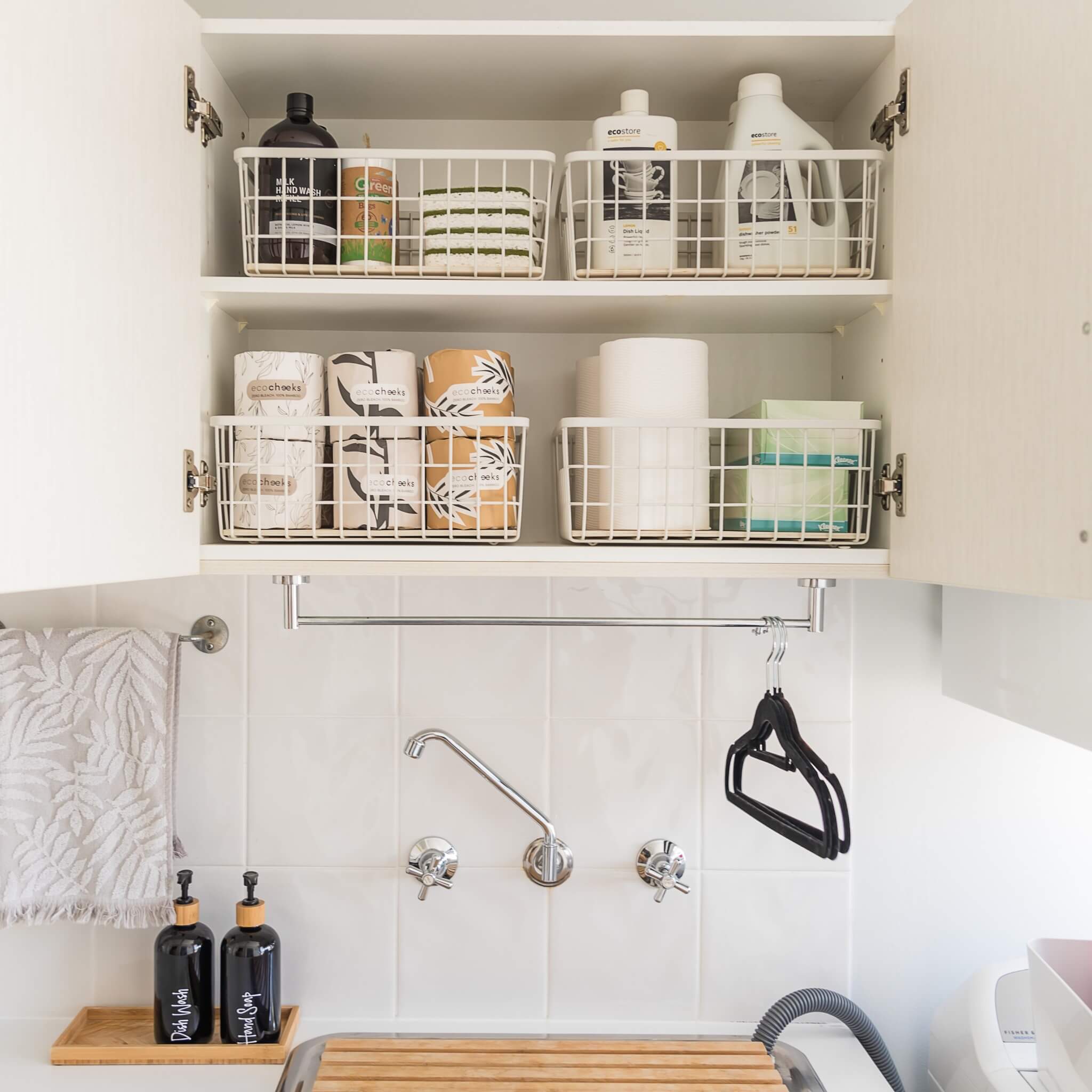  Metal basket storing bottles and jars upright in a kitchen and laundry setting.